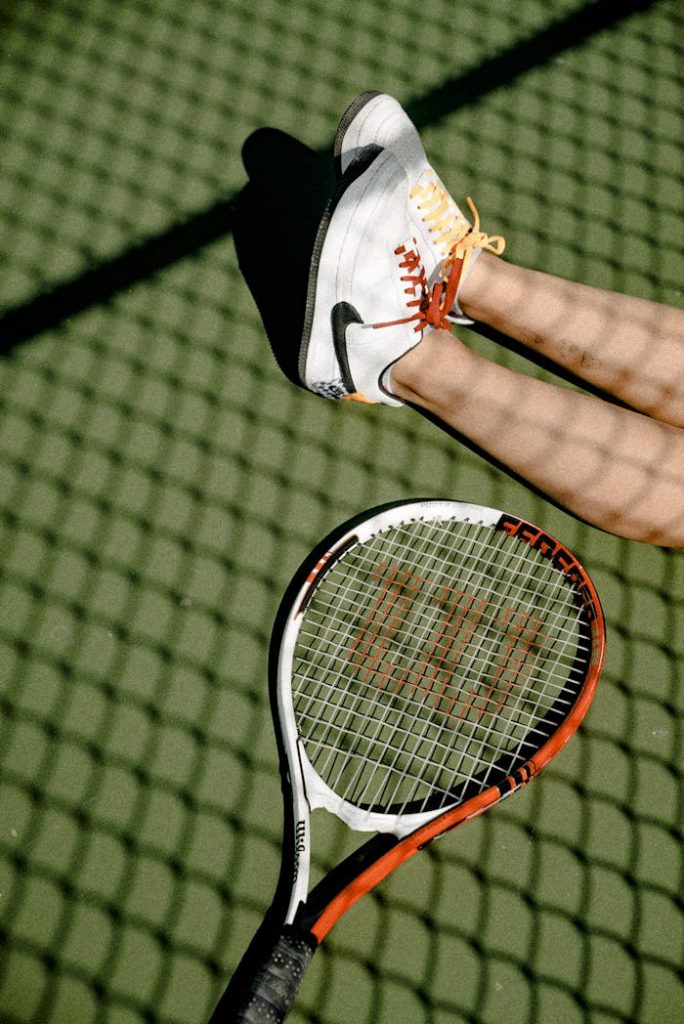 Tennis player in action on an outdoor court with sneakers and racket.